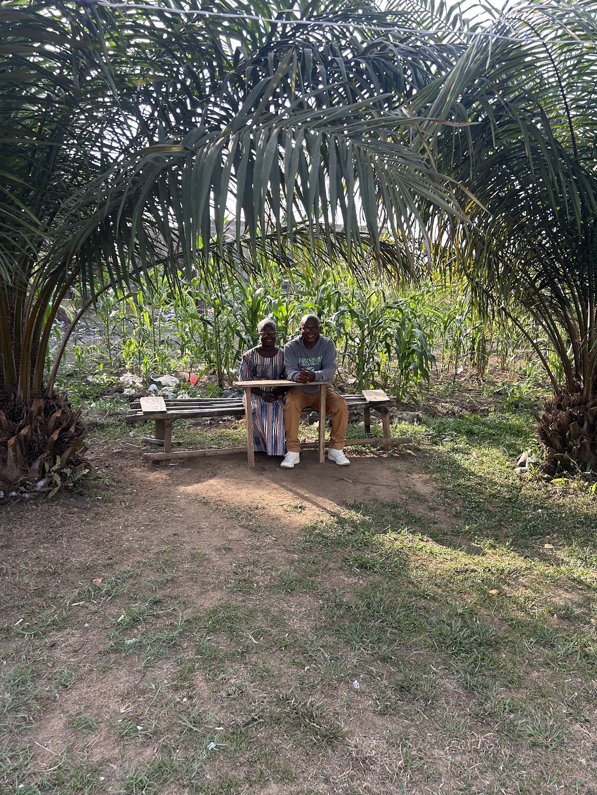Pastor Sallee and Mother Kolu seated in the garden between rows of maize